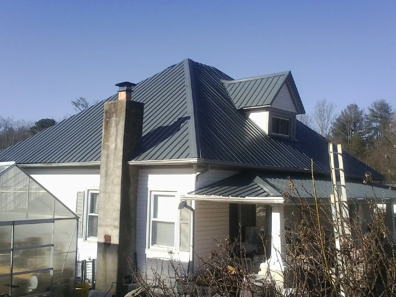 Dark blue standing seam metal roof on a white farmhouse with dormer — Slate & Tile Roof Repair by Roofing Brothers in Nine Mile Falls