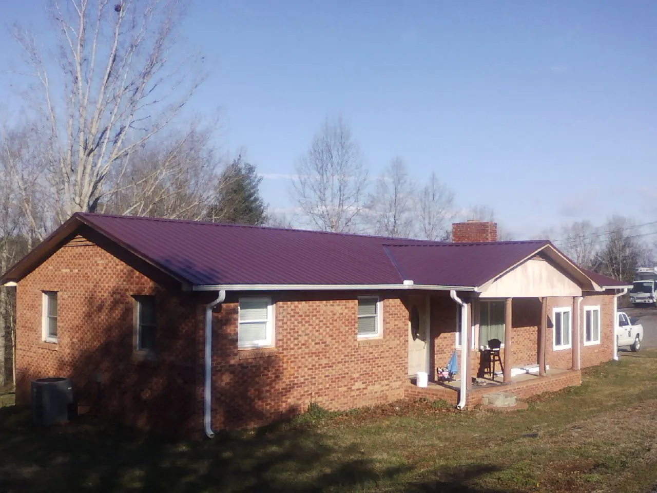 Burgundy metal roof on a brick ranch home with a new addition in Nine Mile Falls