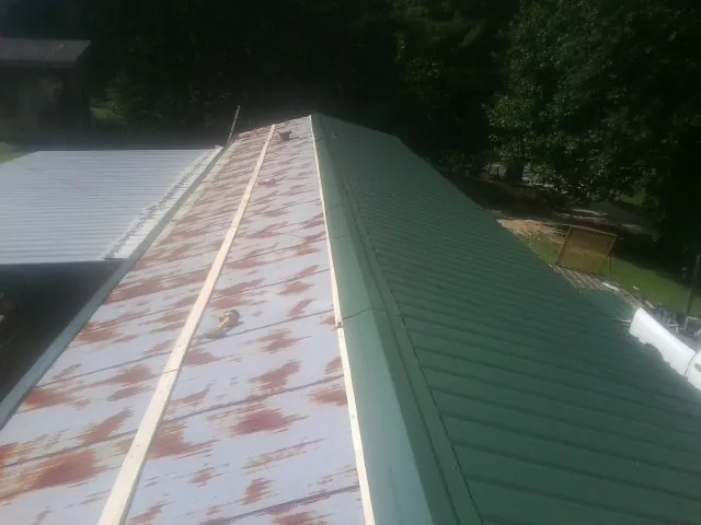 Old rusted panels beside newly installed green metal roofing — Wind Damage Roof Repair by Roofing Brothers in Nine Mile Falls