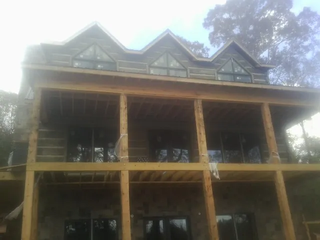 Dormers and porch framing on a large log home under construction — Roof Coating work by our crew in Nine Mile Falls