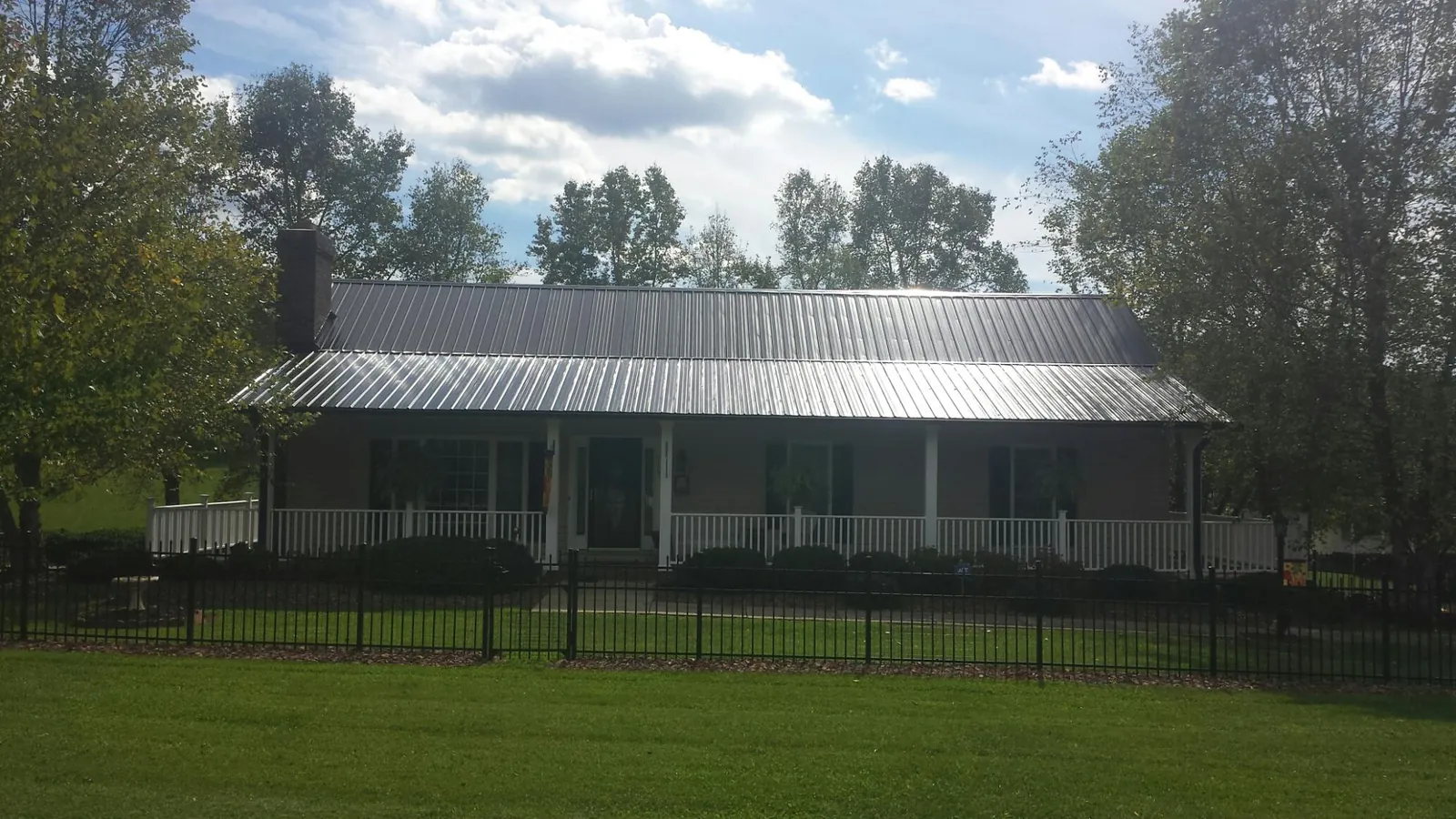 Gray metal roof on a brick ranch with a full width front porch — Gutter Guard Installation work by our crew in Nine Mile Falls