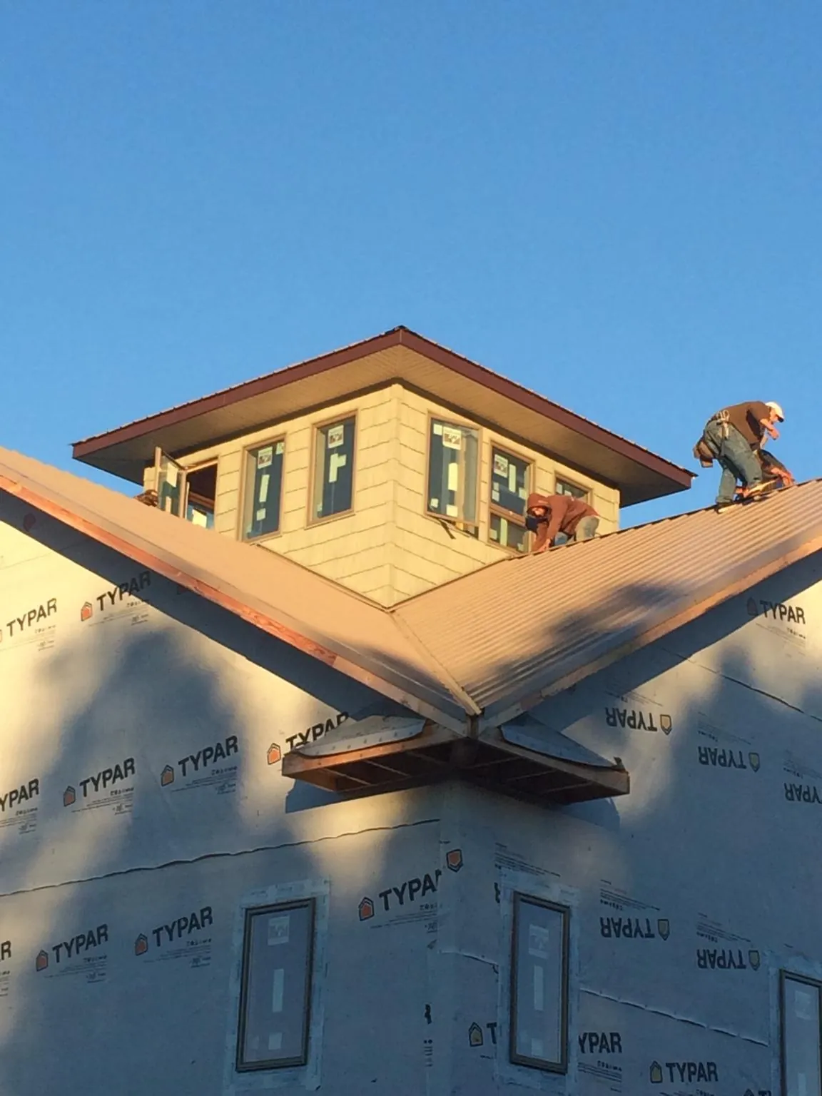 Roofers working around a rooftop cupola on a new metal roof at sunset — Roof Waterproofing in Nine Mile Falls by Roofing Brothers
